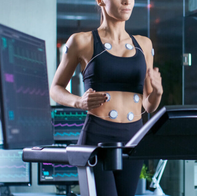 Beautiful,Woman,Athlete,Runs,On,A,Treadmill,With,Electrodes,Attached