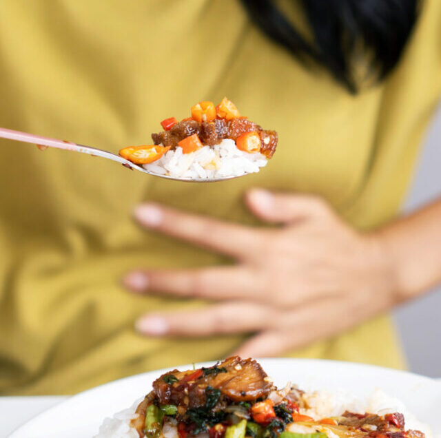 Asian,Woman,Eating,Spicy,Food,And,Having,Acid,Reflux,Or